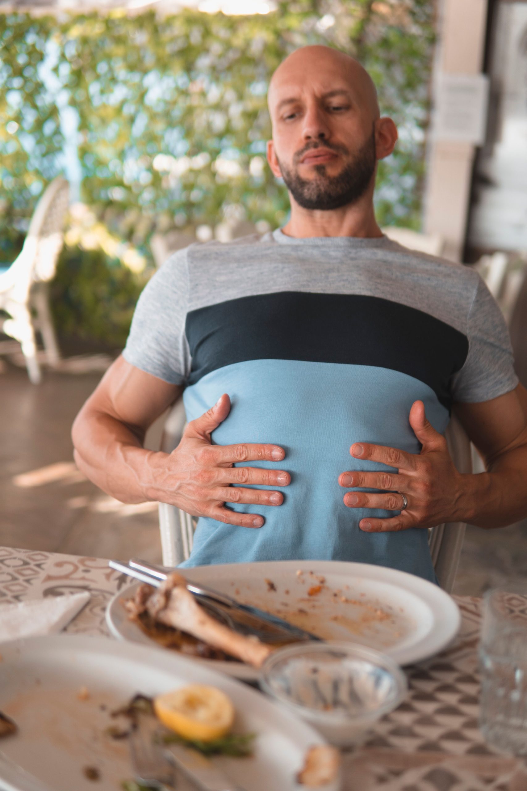 Persona sujetándose la parte baja de la espalda tras terminar de comer, posible dolor de espalda después de comer de origen digestivo